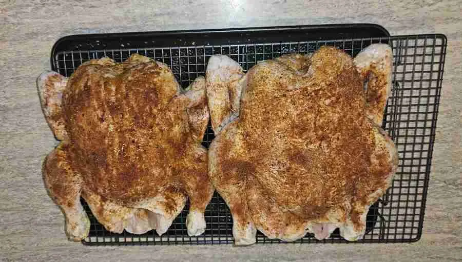 Dry-rub-chicken Two whole chickens seasoned with a dry rub on a wire rack.