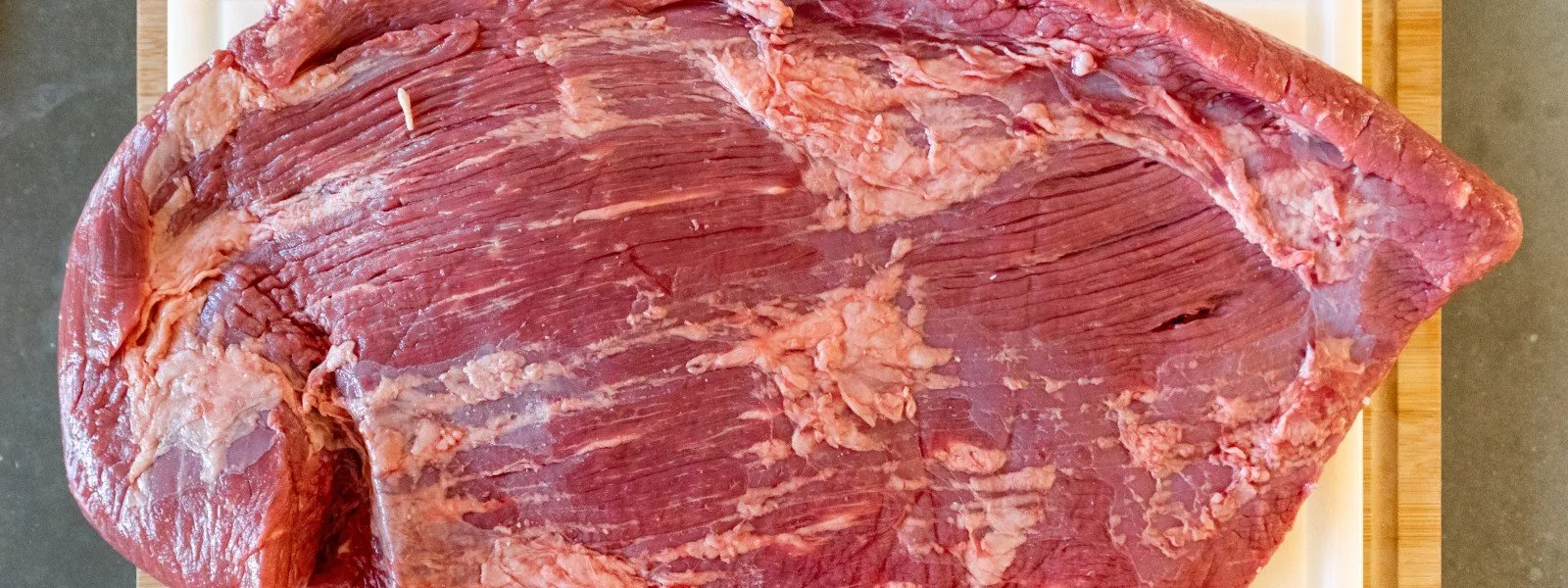 Raw-brisket Raw brisket on a cutting board ready for seasoning, showcasing intricate marbling ideal for smoking, indicative of flavor and juiciness.