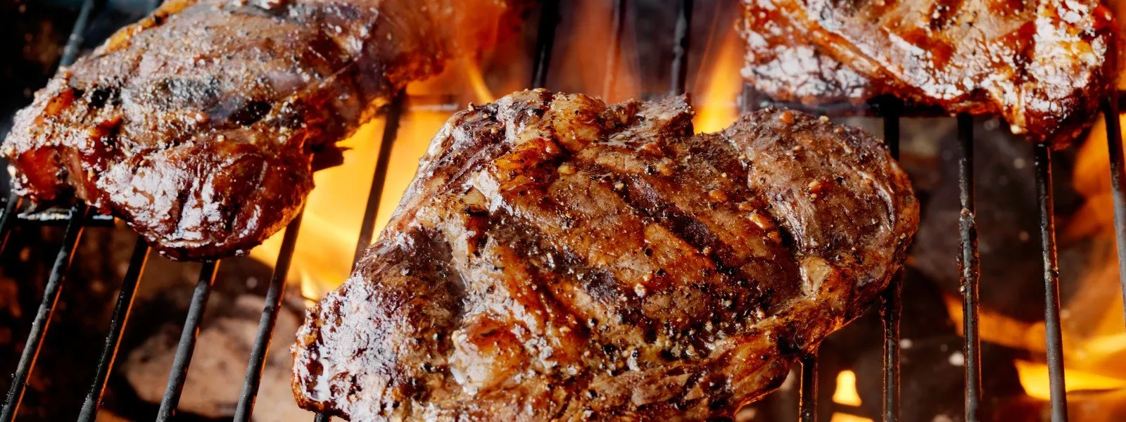 Searing-on-barrel-smoker Succulent steaks sizzling over the glowing embers on a barrel smoker, with a spice-crusted surface ready to tantalize the taste buds.