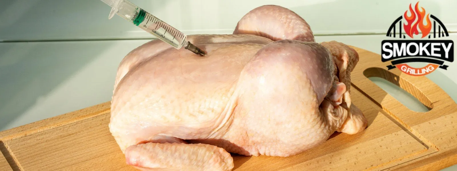 Raw whole chicken on a wooden cutting board being injected with marinade for flavor enhancement