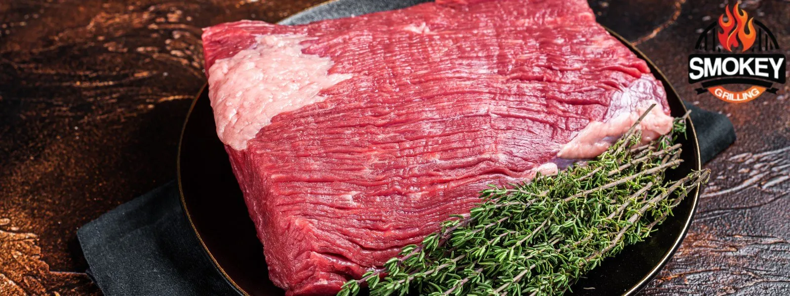 Raw-brisket-with-thyme Raw brisket with thyme on a black plate.